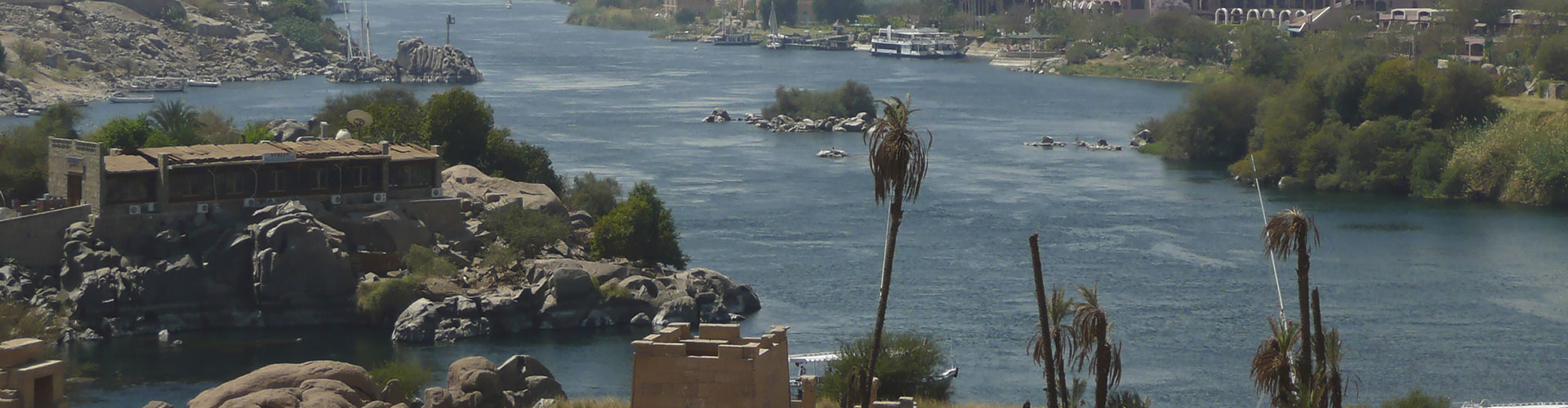 The Nile flowing past granite boulders and palms at Aswan