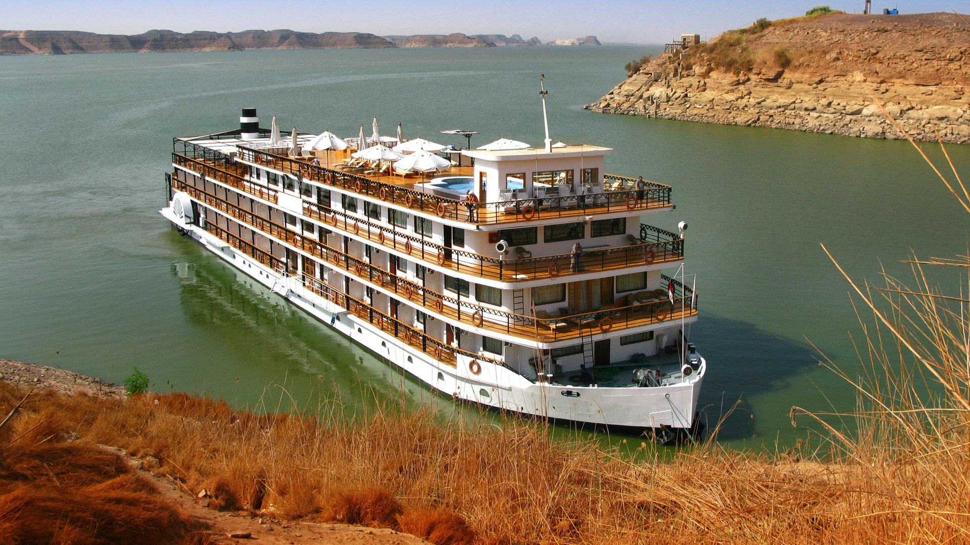 Classic-style riverboat moored below dry desert hills