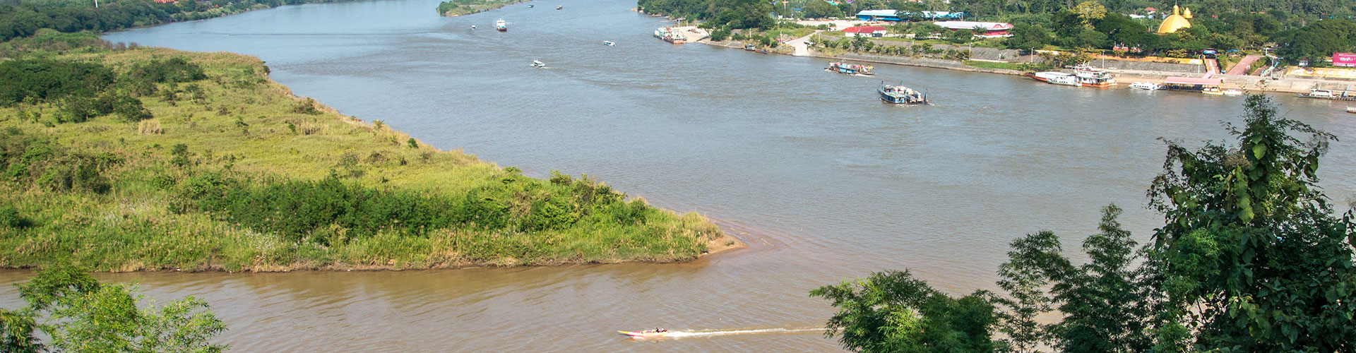 Wide tropical river bend with a riverside town and boats