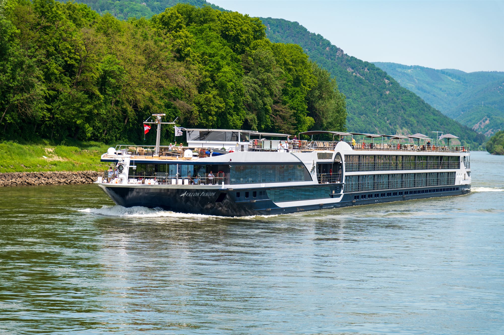 River cruise ship on the Danube at sunset below a historic European town River cruise ship on the Danube at sunset below a historic European town